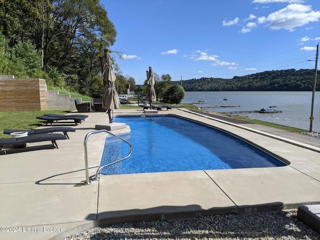 view of pool featuring a water view and a patio