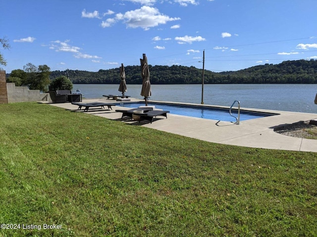 view of pool with a water view and a yard