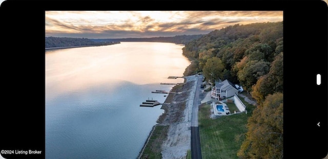 aerial view at dusk featuring a water view