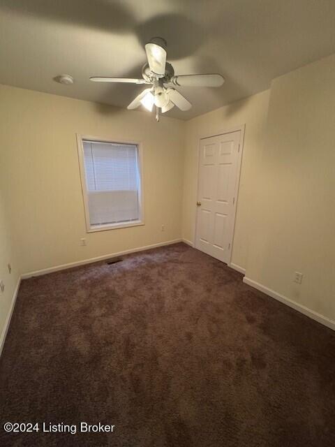 unfurnished room featuring ceiling fan and dark carpet