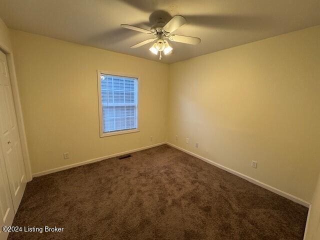 unfurnished bedroom with dark colored carpet and ceiling fan