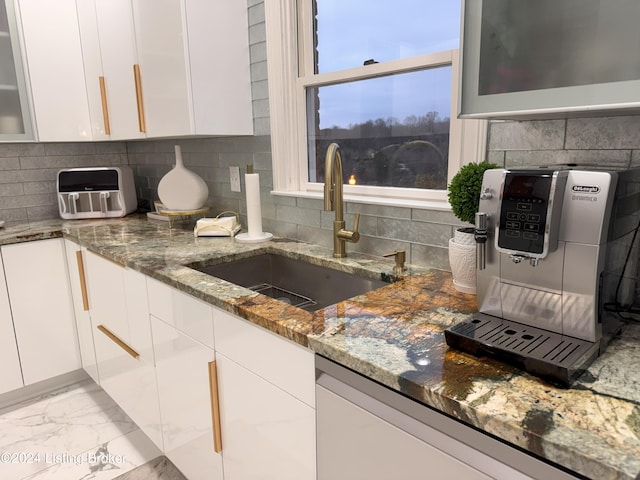 kitchen with white cabinets, dishwashing machine, dark stone counters, and sink