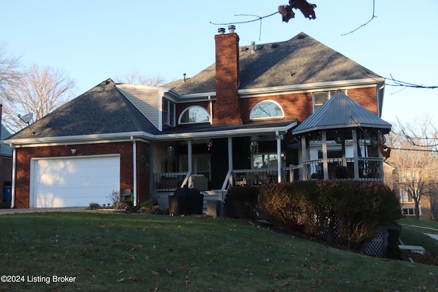 rear view of house featuring a yard, covered porch, and a garage