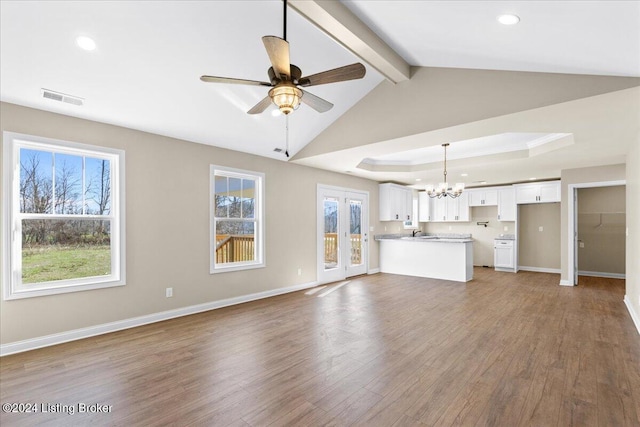 unfurnished living room with hardwood / wood-style floors, ceiling fan with notable chandelier, vaulted ceiling with beams, and a wealth of natural light