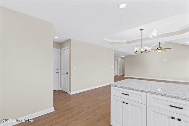 kitchen with white cabinets, ceiling fan with notable chandelier, dark hardwood / wood-style floors, decorative light fixtures, and light stone counters