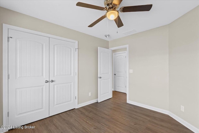 unfurnished bedroom with ceiling fan, dark wood-type flooring, and a closet