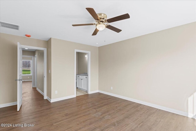 unfurnished bedroom featuring connected bathroom, hardwood / wood-style flooring, and ceiling fan