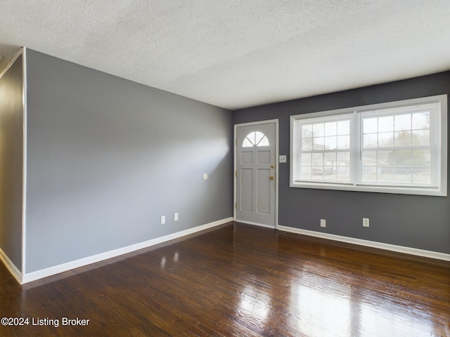 entrance foyer with dark hardwood / wood-style flooring and a textured ceiling