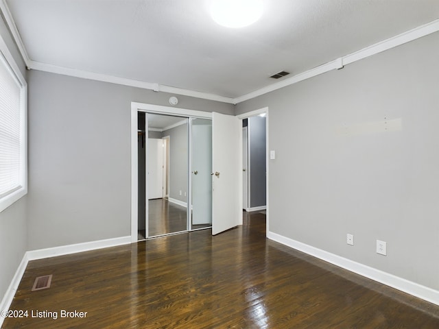 unfurnished bedroom with crown molding, a closet, and dark hardwood / wood-style floors