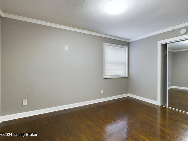 unfurnished bedroom featuring dark hardwood / wood-style flooring, a closet, and crown molding