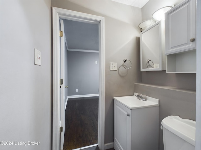 bathroom featuring wood-type flooring, vanity, toilet, and crown molding