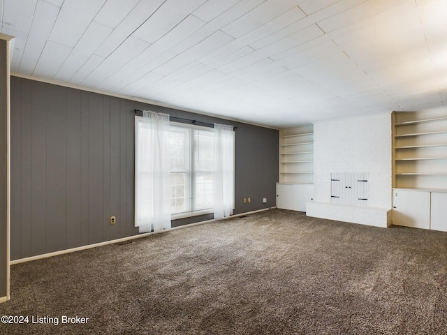 interior space featuring carpet flooring, built in shelves, and wood walls