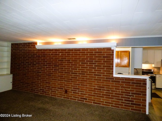 basement with dark colored carpet and brick wall