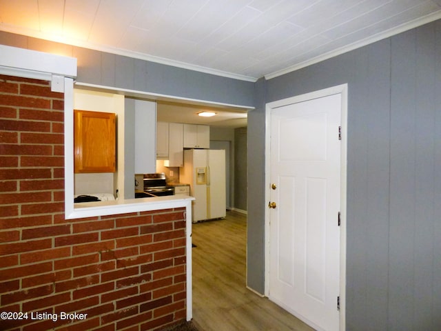 kitchen featuring ornamental molding, stainless steel range, white refrigerator with ice dispenser, wood-type flooring, and white cabinets