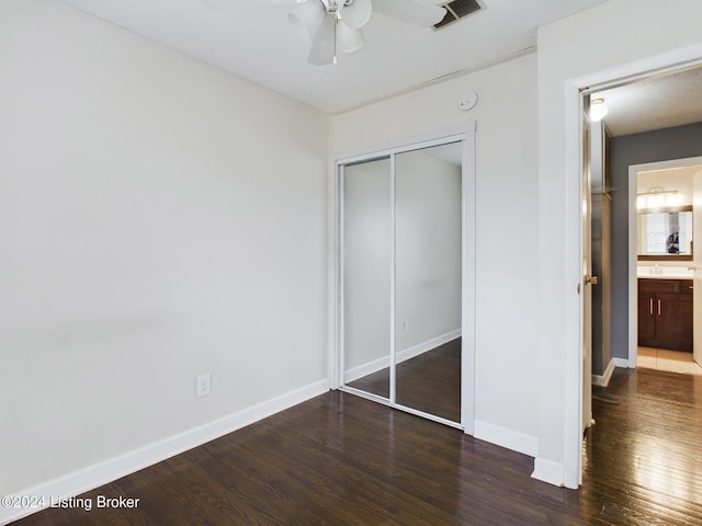 unfurnished bedroom with ceiling fan, dark wood-type flooring, and a closet