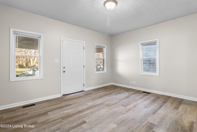 unfurnished room with a textured ceiling and light hardwood / wood-style floors