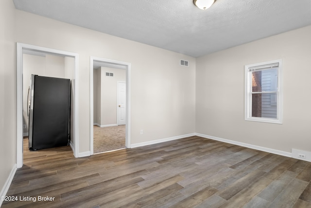 spare room featuring hardwood / wood-style floors and a textured ceiling