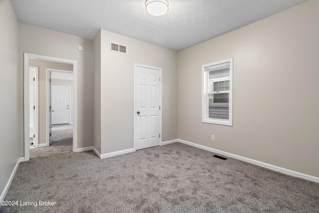 unfurnished bedroom with carpet floors, a textured ceiling, and a closet