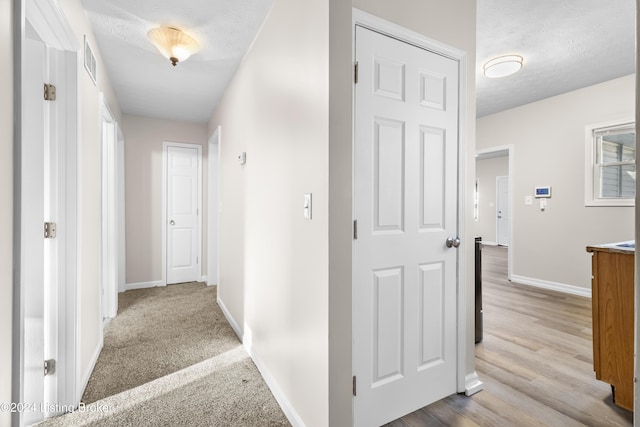 corridor with light hardwood / wood-style floors and a textured ceiling