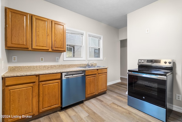 kitchen featuring sink, stainless steel appliances, a textured ceiling, and light wood-type flooring