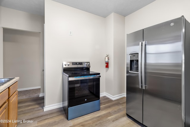 kitchen featuring light wood-type flooring, stainless steel refrigerator with ice dispenser, and electric range oven