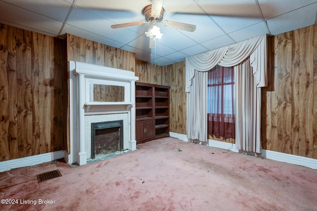 unfurnished living room with a paneled ceiling and wood walls