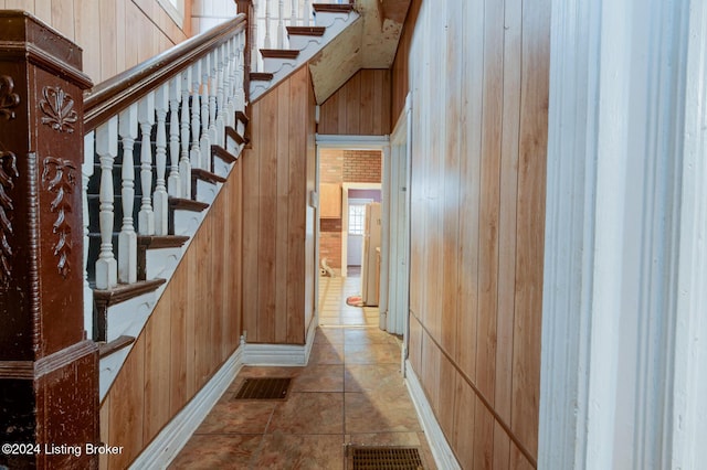 stairway featuring tile patterned floors and wooden walls