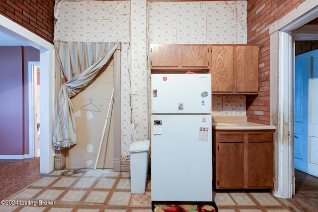 kitchen with white refrigerator and brick wall