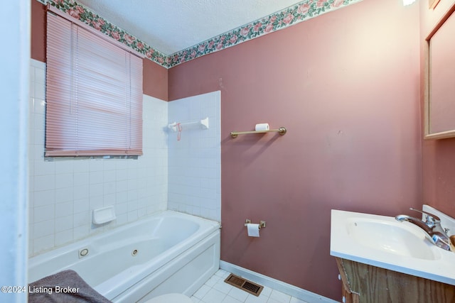 bathroom with tile patterned floors, a tub, vanity, and a textured ceiling