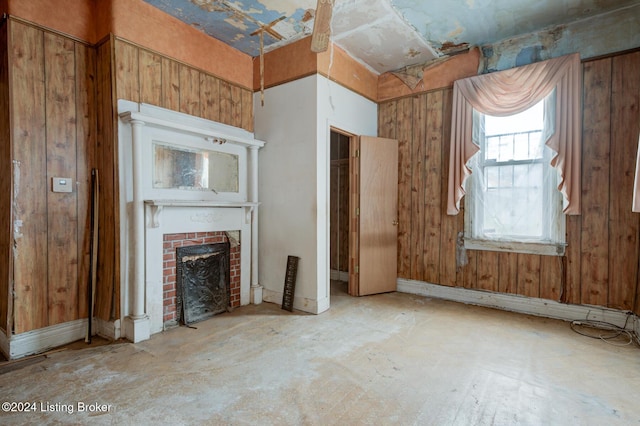 unfurnished living room with a fireplace and wood walls