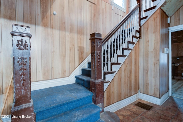 stairway featuring wooden walls