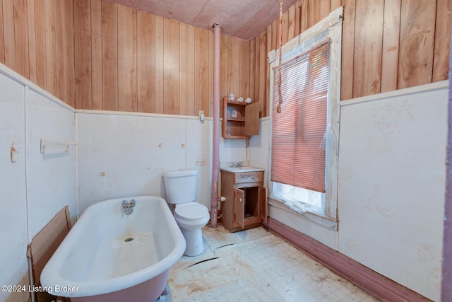 bathroom with wooden walls, a washtub, and toilet