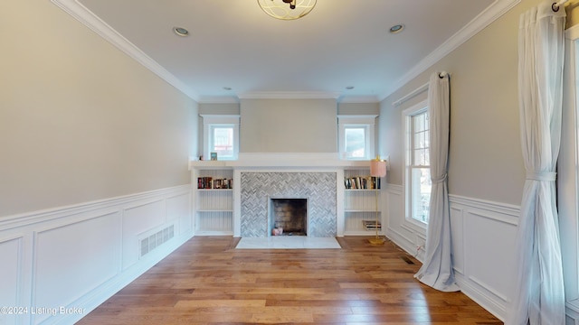 unfurnished living room featuring a tile fireplace, light wood-type flooring, and ornamental molding