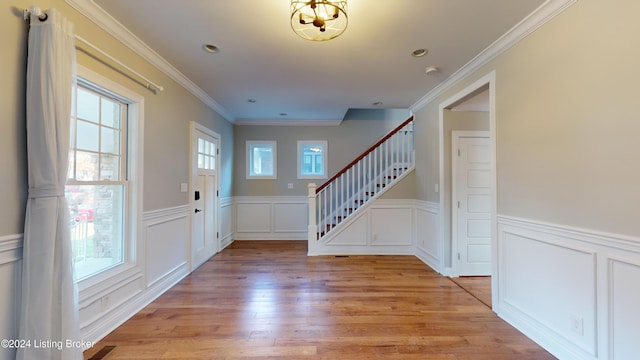 entrance foyer featuring light hardwood / wood-style floors, plenty of natural light, and crown molding