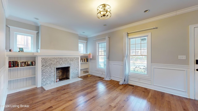 unfurnished living room featuring crown molding, a fireplace, a healthy amount of sunlight, and hardwood / wood-style flooring