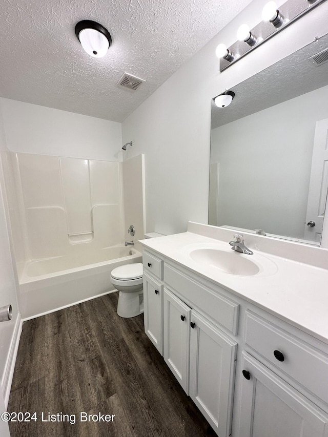 full bathroom featuring wood-type flooring,  shower combination, a textured ceiling, toilet, and vanity