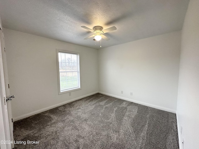 spare room with ceiling fan, dark carpet, and a textured ceiling