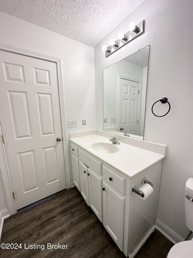 bathroom featuring vanity, a textured ceiling, hardwood / wood-style flooring, and toilet