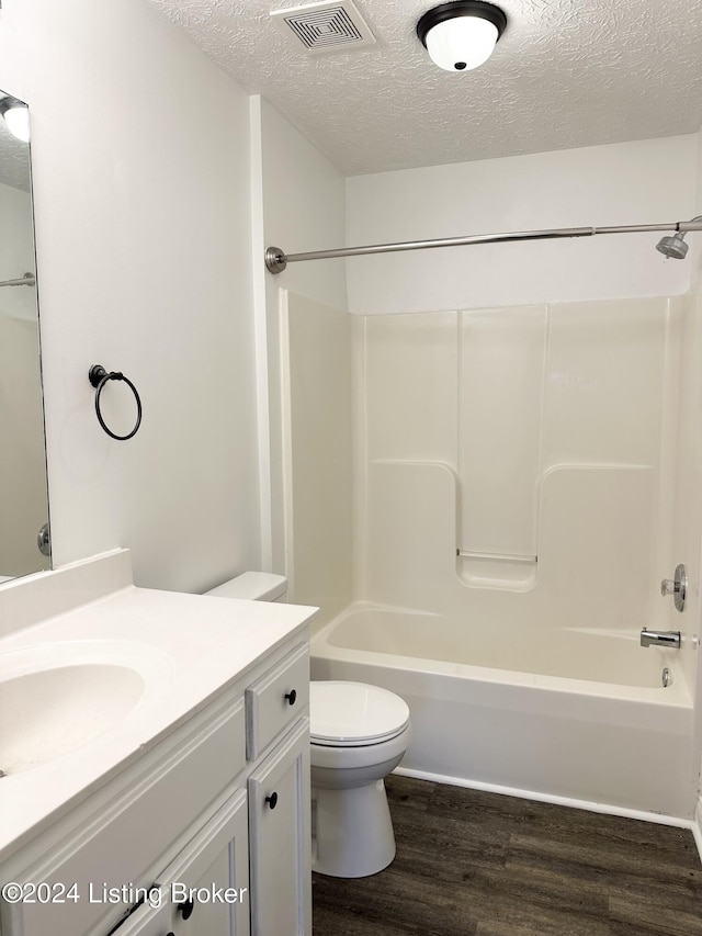 full bathroom featuring hardwood / wood-style flooring, toilet, and a textured ceiling