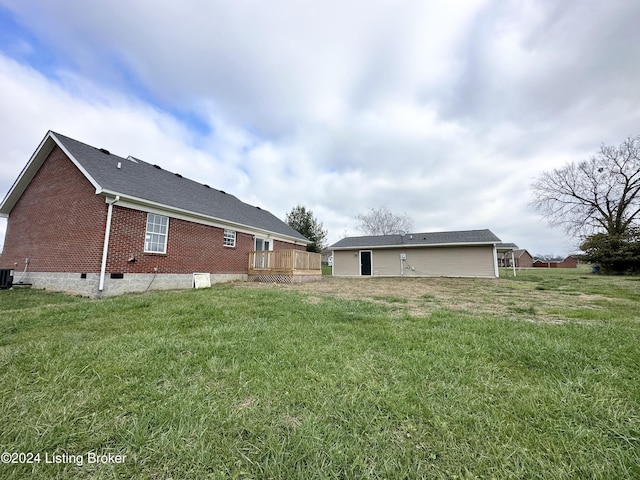 rear view of property featuring a lawn, a deck, and central air condition unit