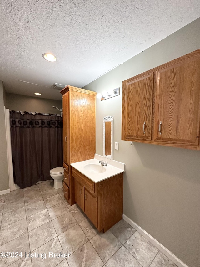 bathroom featuring a textured ceiling, vanity, toilet, and tile patterned floors