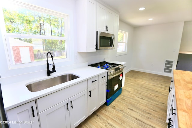 kitchen featuring wooden counters, sink, light hardwood / wood-style flooring, white cabinetry, and stainless steel appliances