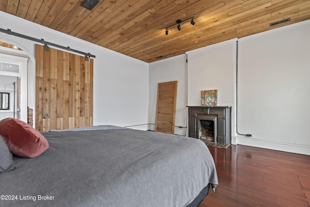 bedroom with a barn door, crown molding, dark wood-type flooring, and wooden ceiling