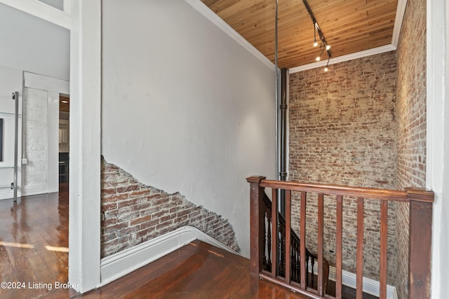 stairway with crown molding, wood ceiling, brick wall, and wood-type flooring