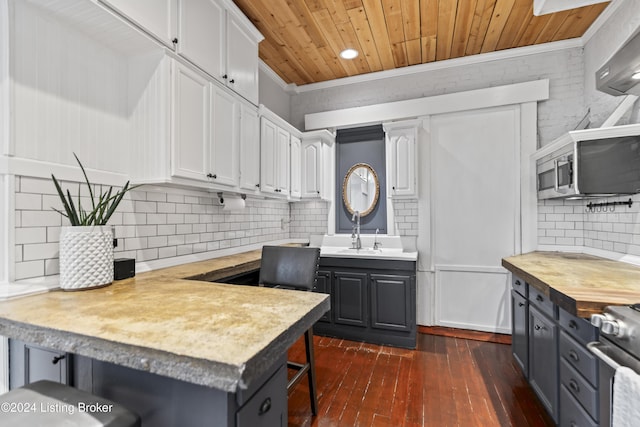 kitchen featuring a breakfast bar, white cabinets, dark wood-type flooring, and ornamental molding