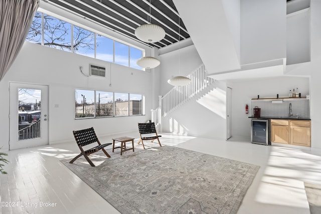 interior space featuring a high ceiling, light hardwood / wood-style flooring, wine cooler, and indoor wet bar