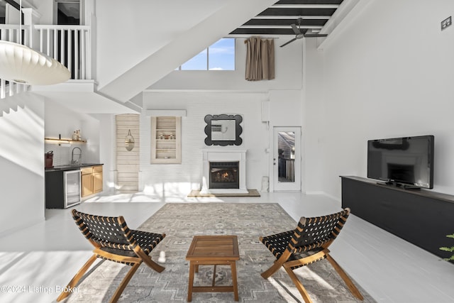 living room with wine cooler, beamed ceiling, a high ceiling, and indoor wet bar