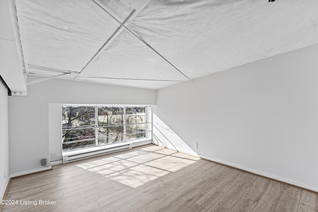 interior space featuring a baseboard radiator, vaulted ceiling, and hardwood / wood-style flooring