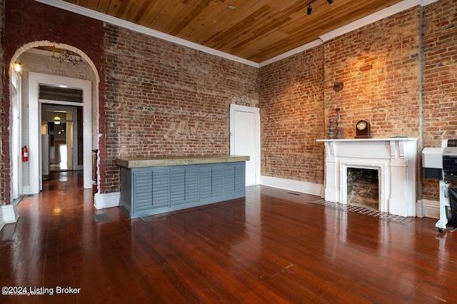 unfurnished living room featuring dark hardwood / wood-style floors, crown molding, and brick wall