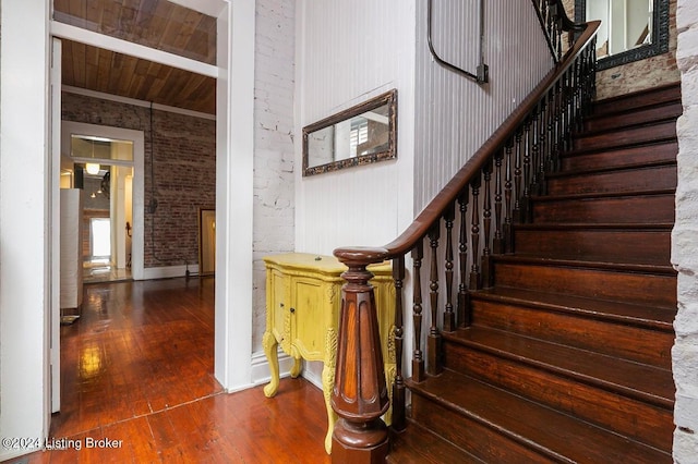 stairway featuring hardwood / wood-style flooring, wooden ceiling, and brick wall